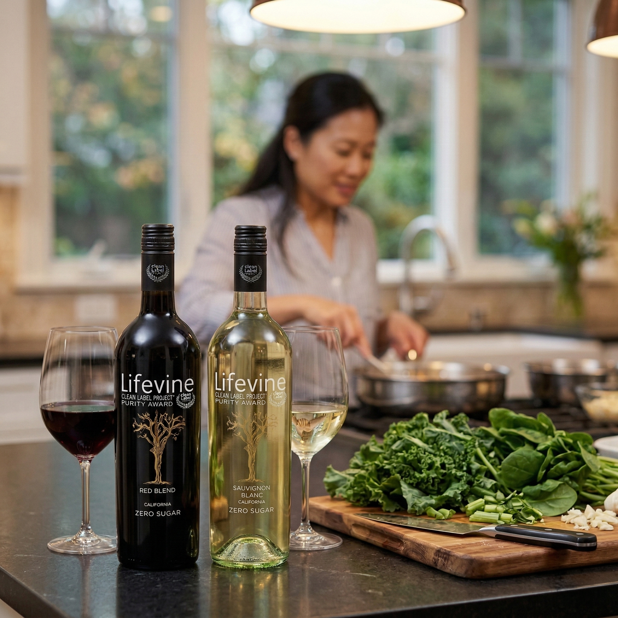 Two bottles of Lifevine wine on a kitchen counter with a woman cooking in the background.
